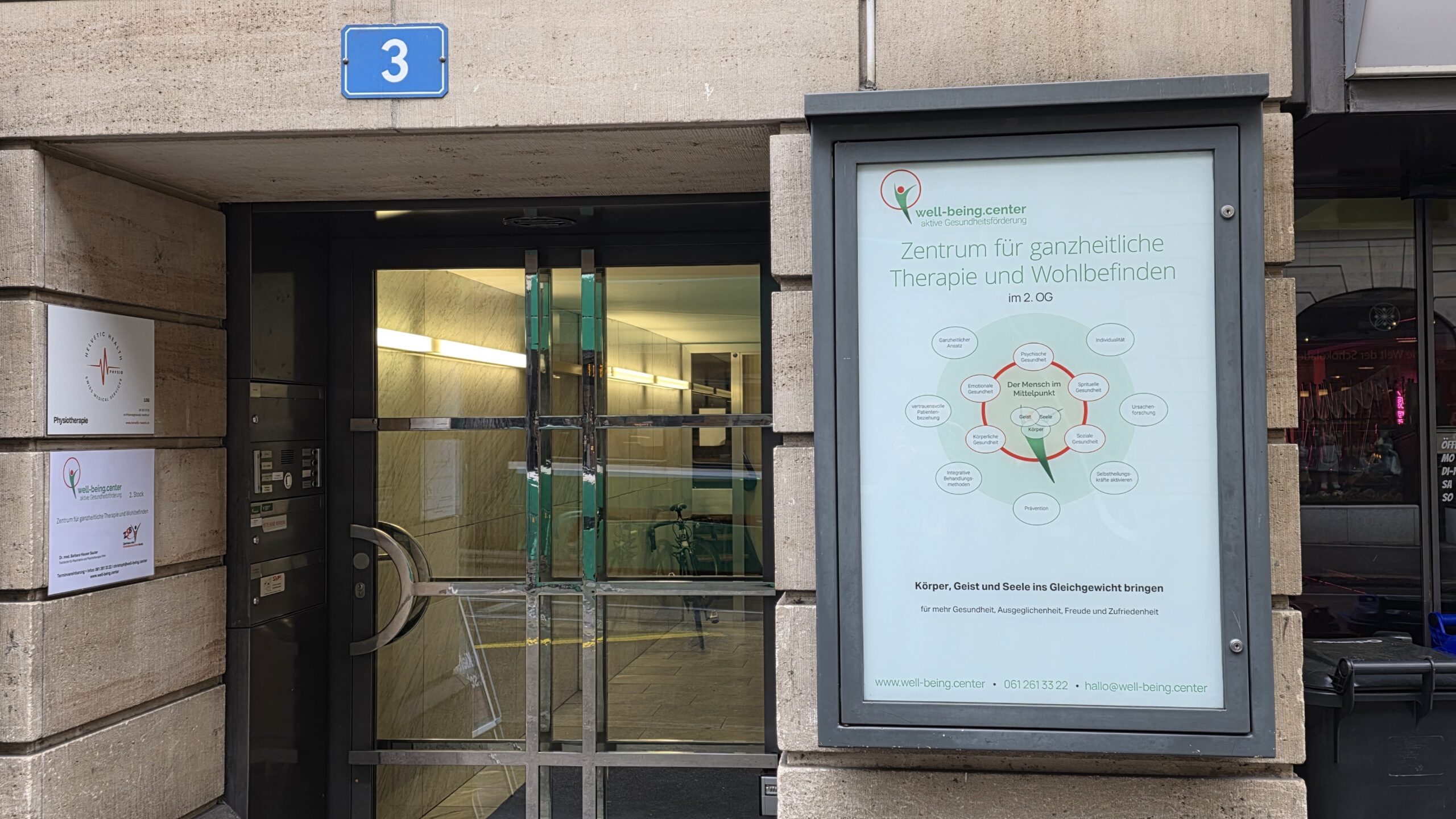 Aussenansicht: Eingang Marktgasse 3 mit Schaukasten des well-being.center Basel